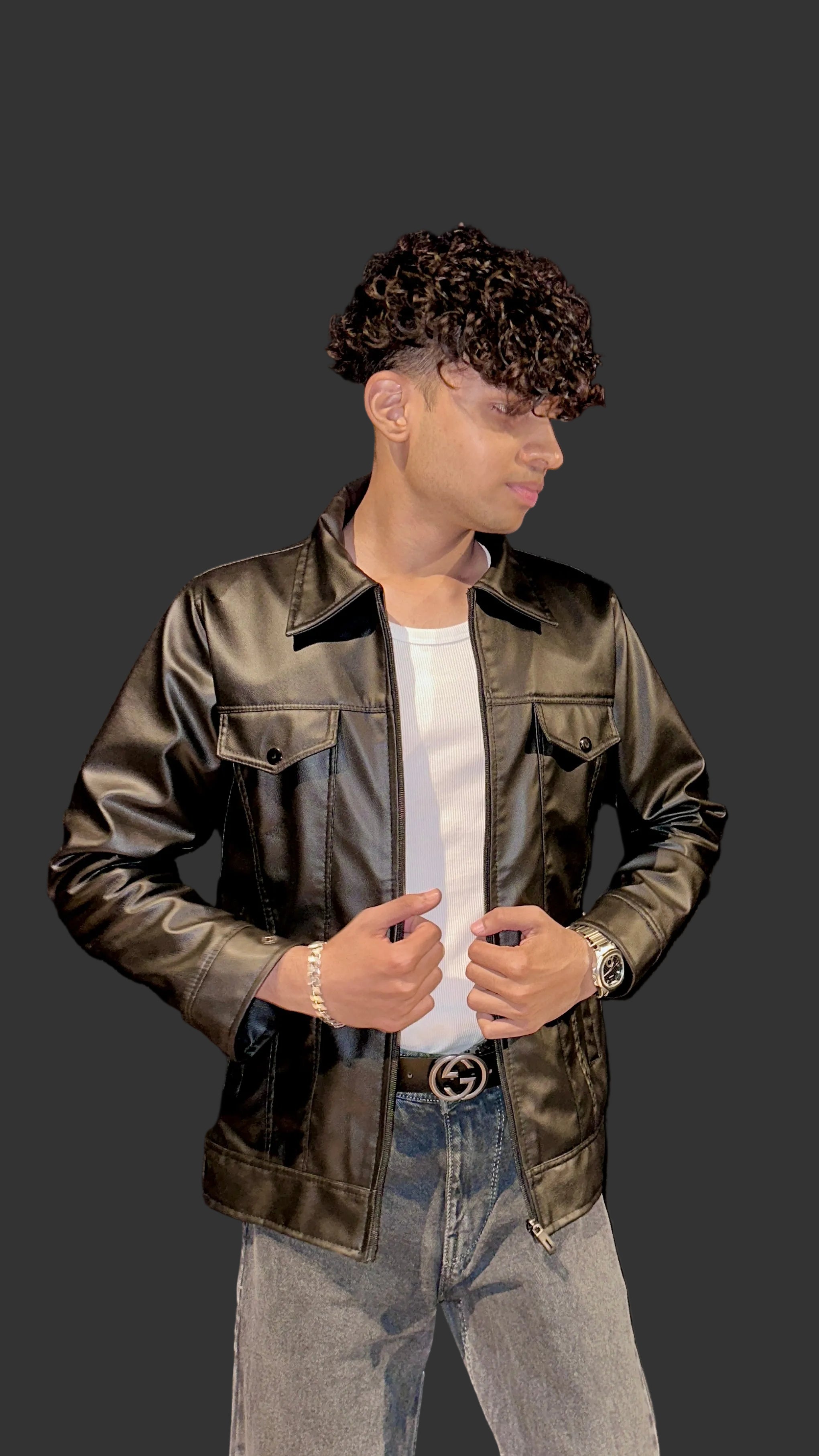 Person wearing a brown leather jacket and gray pants against a black background